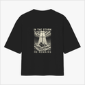 Camiseta com estampa frontal de texto decorativo "OG" e estampa traseira de ilustração com cruz em paisagem tempestuosa e as palavras "In the Storm He Remains".