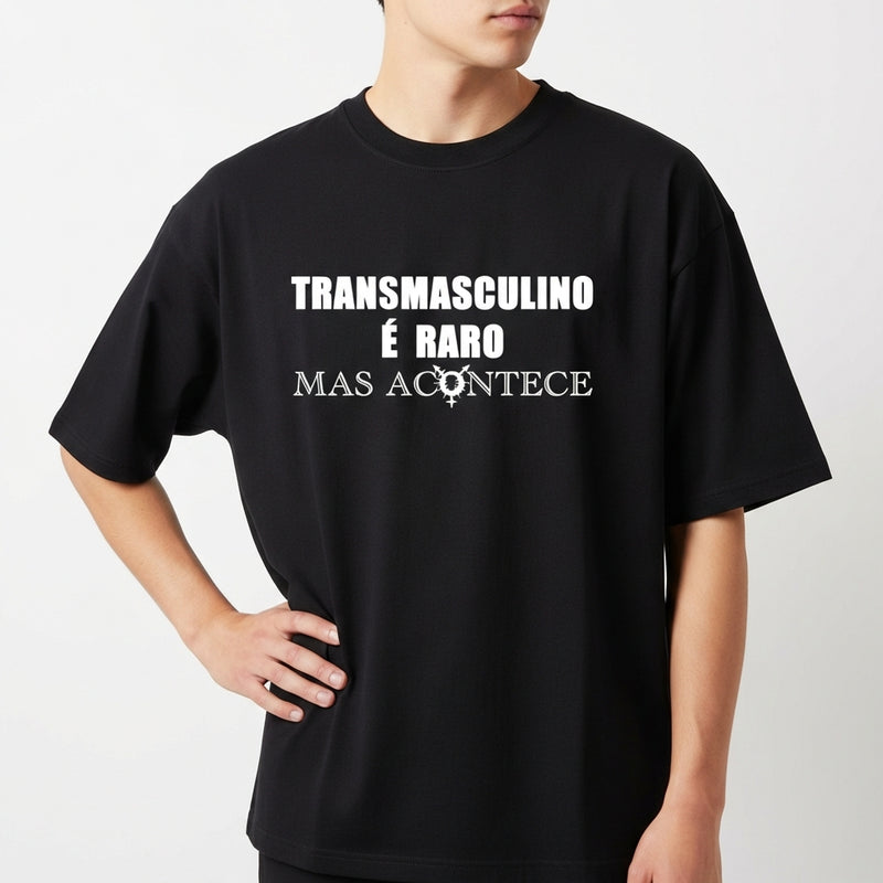 Camiseta com estampa frontal de texto "Transmasculino é raro mas acontece" e ícone; estampa traseira de gráfico circular com a palavra "TRANSVESTICO".